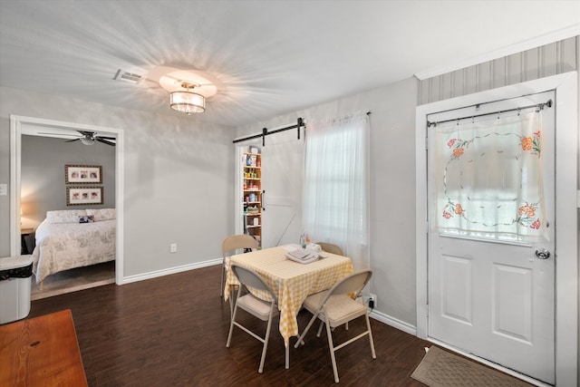 dining space with a barn door, dark wood-type flooring, ceiling fan, and a wealth of natural light