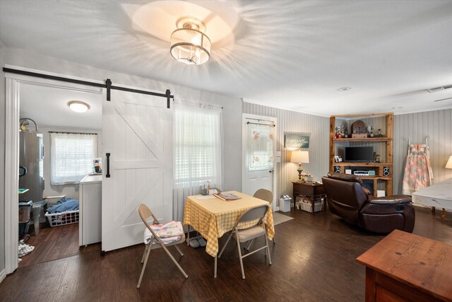 dining space featuring a barn door and dark hardwood / wood-style flooring