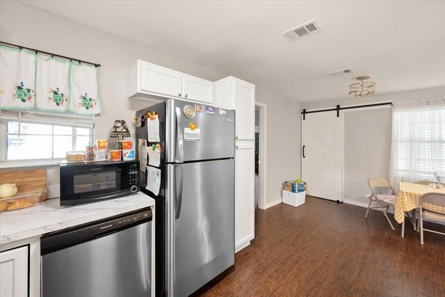 kitchen featuring light stone counters, white cabinetry, appliances with stainless steel finishes, a barn door, and dark hardwood / wood-style flooring