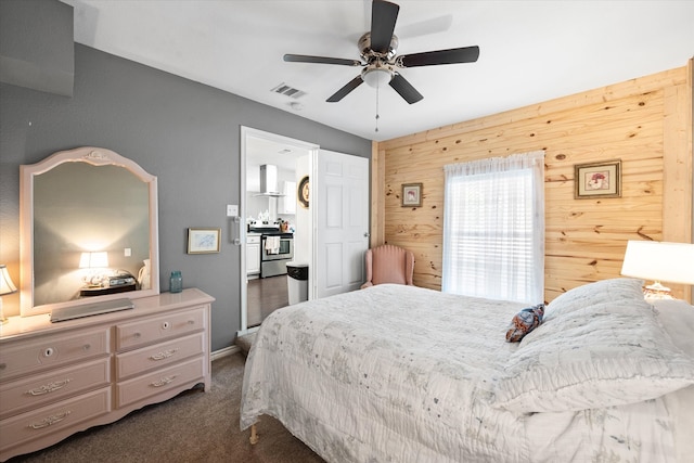 bedroom with ceiling fan, wood walls, and dark carpet