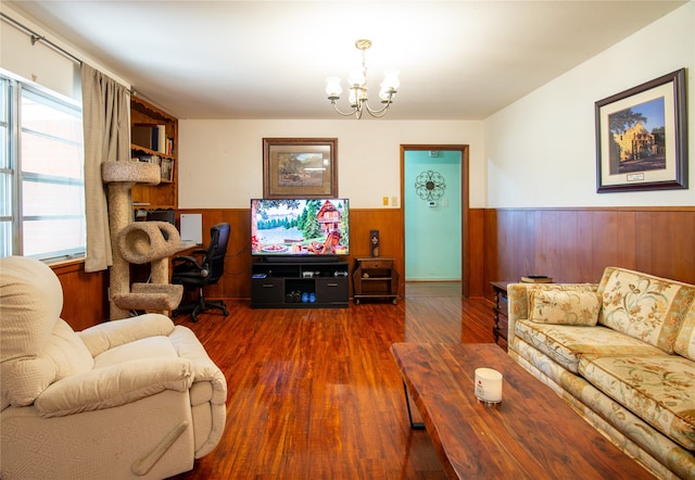 living room featuring an inviting chandelier, dark hardwood / wood-style floors, and wood walls