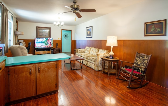 living room with ceiling fan with notable chandelier and dark hardwood / wood-style floors