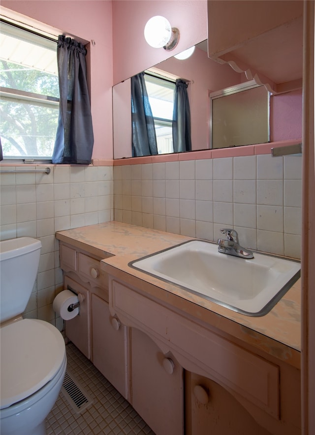 bathroom featuring tasteful backsplash, toilet, tile walls, vanity, and tile patterned flooring