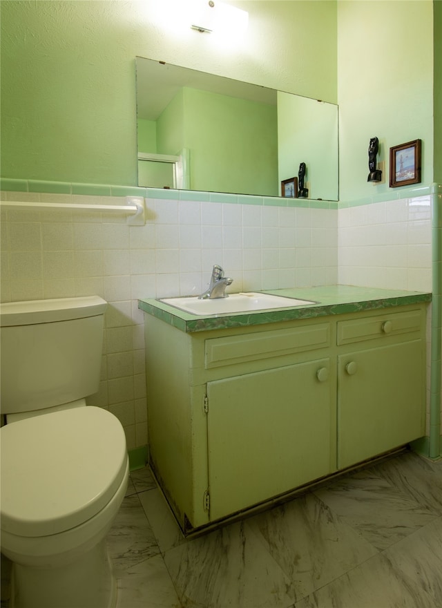 bathroom with vanity, toilet, and tile walls