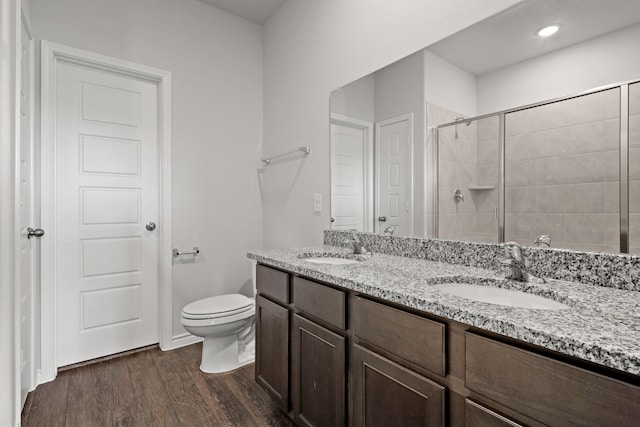 bathroom featuring vanity, toilet, hardwood / wood-style flooring, and a tile shower