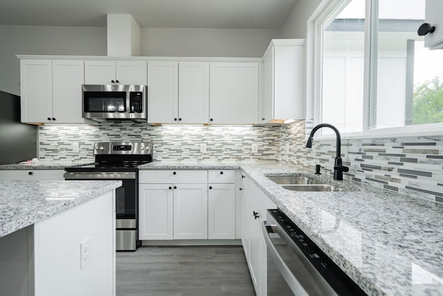 kitchen with backsplash, sink, appliances with stainless steel finishes, light hardwood / wood-style floors, and white cabinetry