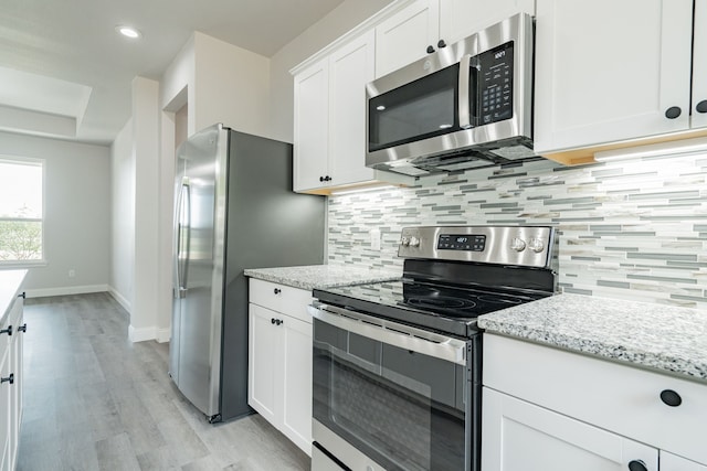 kitchen featuring white cabinetry, light hardwood / wood-style flooring, light stone countertops, and appliances with stainless steel finishes