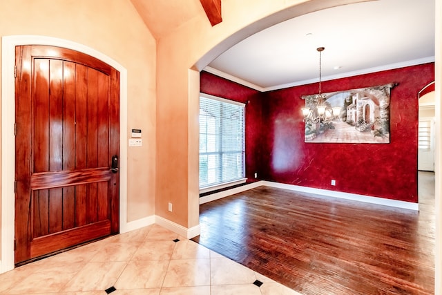 foyer entrance featuring vaulted ceiling with beams, a notable chandelier, wood-type flooring, and ornamental molding