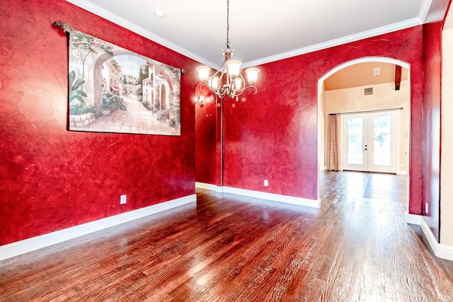 spare room with wood finished floors, baseboards, arched walkways, french doors, and crown molding