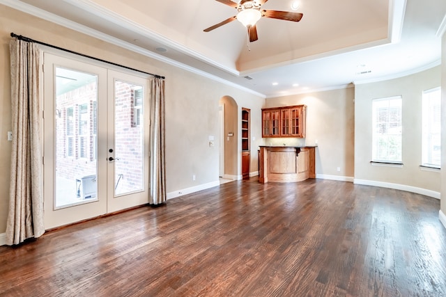 unfurnished living room with a tray ceiling, dark hardwood / wood-style flooring, french doors, and ornamental molding