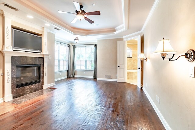 unfurnished living room with visible vents, a ceiling fan, a tray ceiling, and wood finished floors