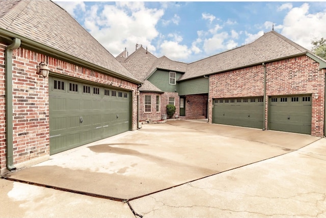 view of front facade with a garage, driveway, and a shingled roof