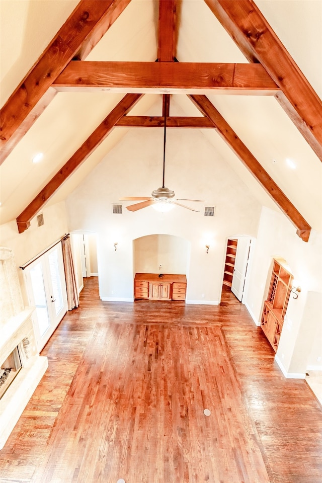 unfurnished living room with beamed ceiling, wood finished floors, and visible vents