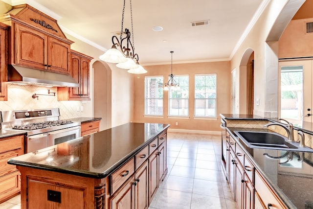 kitchen with double oven range, visible vents, arched walkways, a sink, and under cabinet range hood