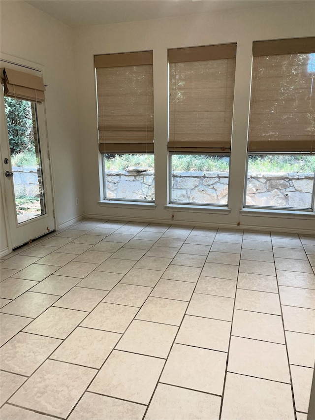 empty room featuring light tile patterned floors and a healthy amount of sunlight