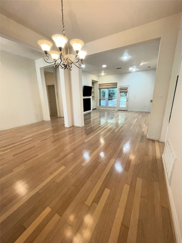 unfurnished living room with a notable chandelier and hardwood / wood-style flooring