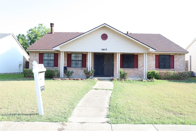 ranch-style house with covered porch, a shingled roof, a front lawn, and brick siding