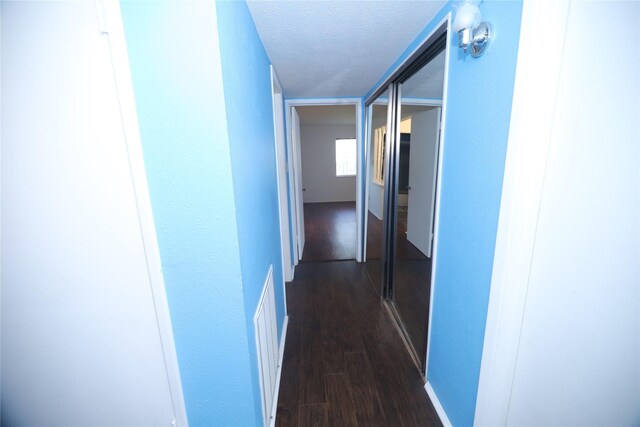 hall with a textured ceiling and dark hardwood / wood-style floors