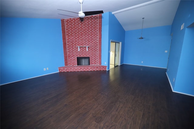 unfurnished living room with ceiling fan, high vaulted ceiling, hardwood / wood-style floors, brick wall, and a brick fireplace