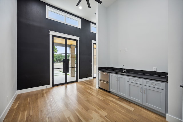 interior space with a towering ceiling, sink, plenty of natural light, and gray cabinetry