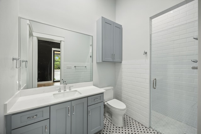 bathroom with vanity, toilet, tile walls, and a shower with door