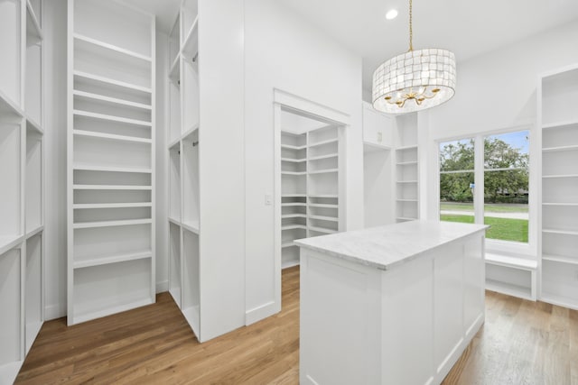 walk in closet featuring an inviting chandelier and hardwood / wood-style floors