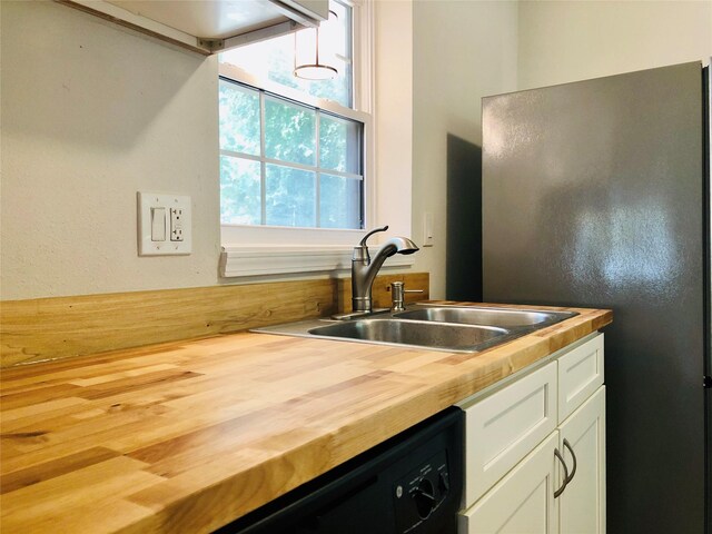 kitchen featuring white cabinets, dishwasher, refrigerator, wood counters, and sink