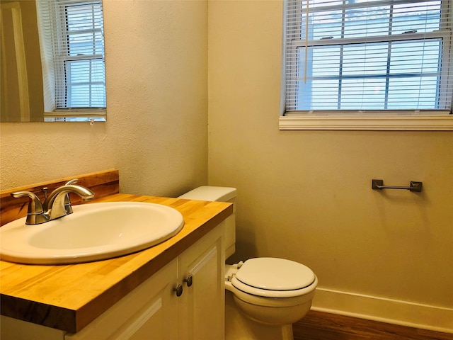 bathroom with hardwood / wood-style flooring, toilet, and vanity