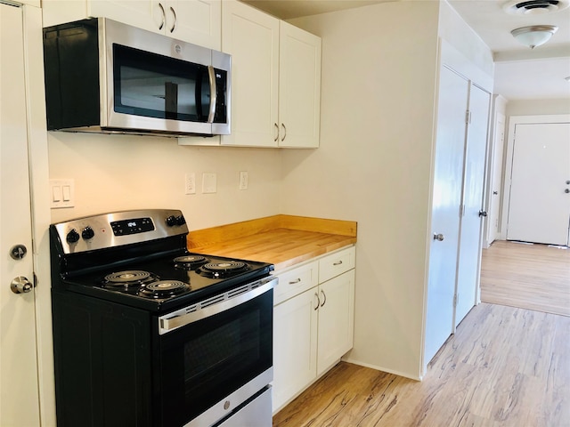 kitchen featuring light hardwood / wood-style floors, appliances with stainless steel finishes, white cabinets, and wood counters