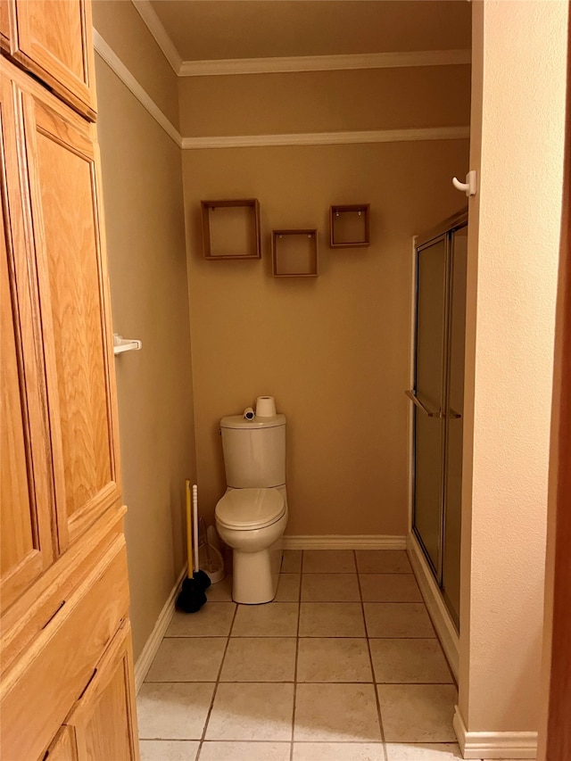 bathroom featuring tile patterned flooring, a shower with shower door, toilet, and ornamental molding