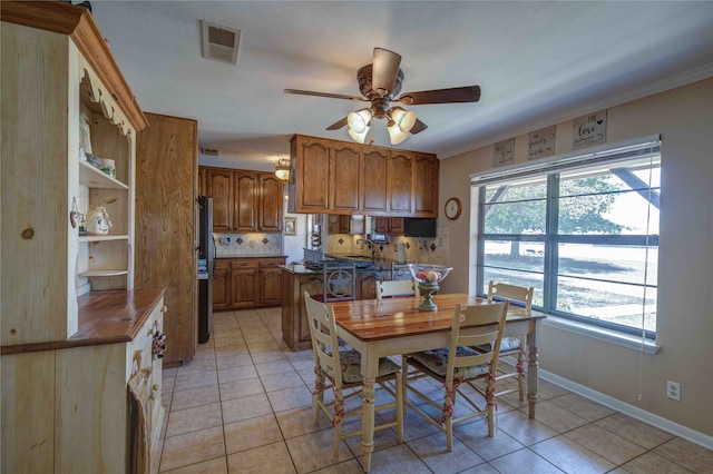 tiled dining area with crown molding and ceiling fan