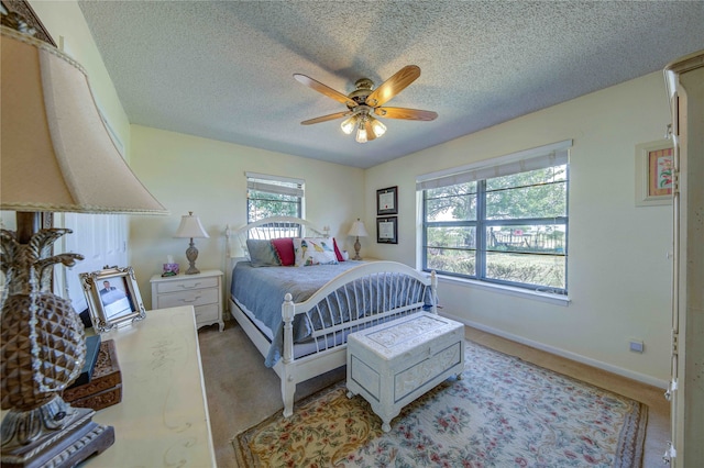 bedroom with ceiling fan, light colored carpet, and a textured ceiling