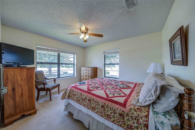 bedroom with ceiling fan, carpet floors, a textured ceiling, and multiple windows