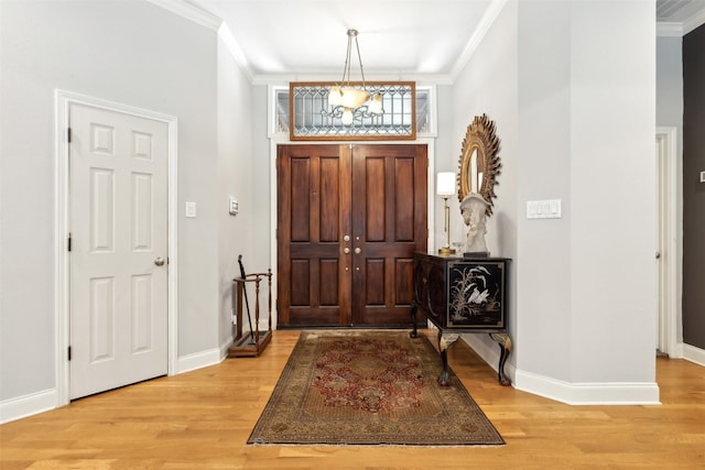 entrance foyer featuring crown molding, a chandelier, and light wood-type flooring