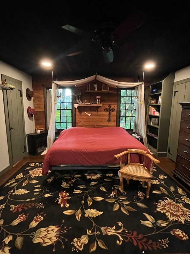 bedroom featuring wooden walls and multiple windows