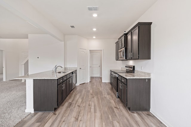 kitchen with dark brown cabinets, stainless steel appliances, and light hardwood / wood-style flooring