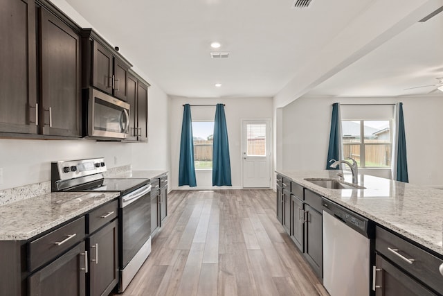 kitchen with appliances with stainless steel finishes, light hardwood / wood-style floors, a healthy amount of sunlight, and sink