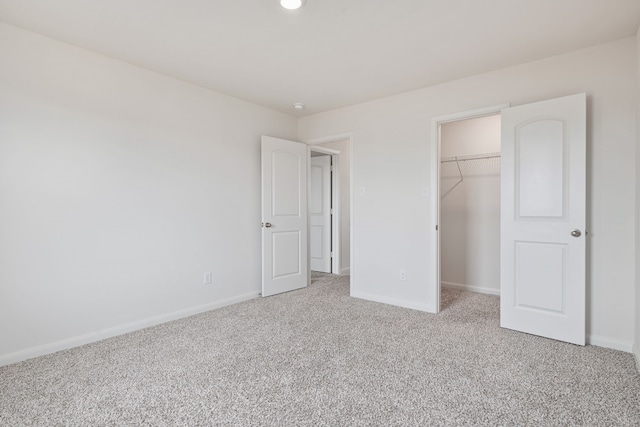 unfurnished bedroom with a walk in closet, carpet floors, and a closet