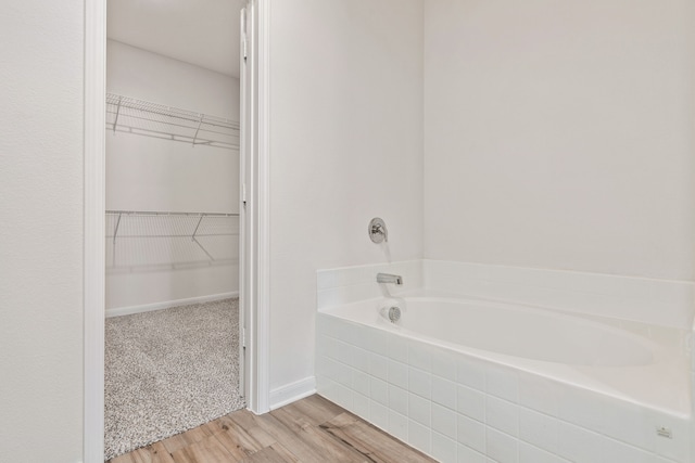 bathroom featuring wood-type flooring and tiled bath