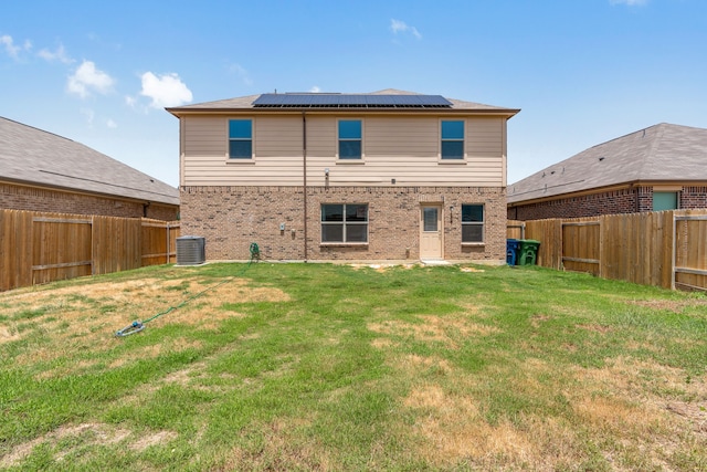 back of property with solar panels, a yard, and central AC