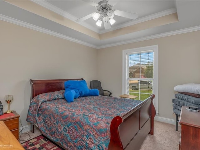 carpeted bedroom with ornamental molding, ceiling fan, and a tray ceiling