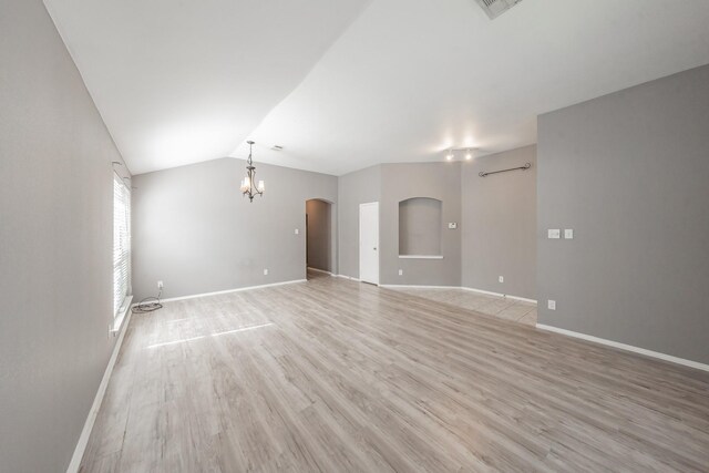 spare room featuring hardwood / wood-style flooring, lofted ceiling, and an inviting chandelier