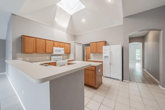 kitchen with a skylight, sink, a center island, light tile patterned floors, and white appliances