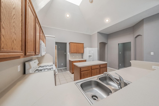 kitchen with white appliances, sink, kitchen peninsula, lofted ceiling, and light tile patterned flooring