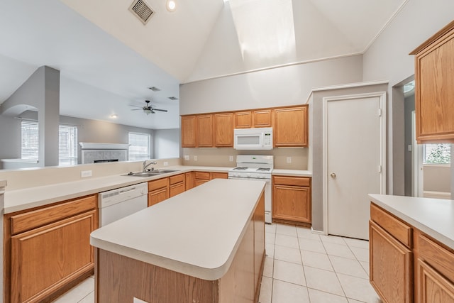 kitchen with light tile patterned flooring, ceiling fan, white appliances, a kitchen island, and a tiled fireplace