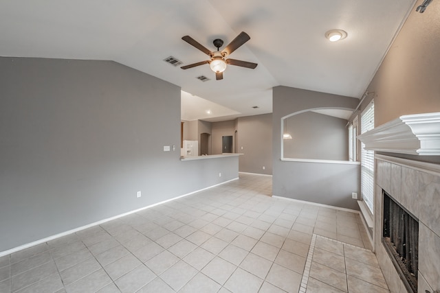 unfurnished living room with light tile patterned flooring, a tiled fireplace, ceiling fan, and vaulted ceiling