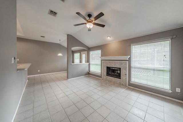 unfurnished living room featuring light tile patterned flooring, ceiling fan, a fireplace, and vaulted ceiling