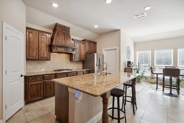 kitchen featuring stainless steel appliances, custom exhaust hood, a kitchen island with sink, and sink