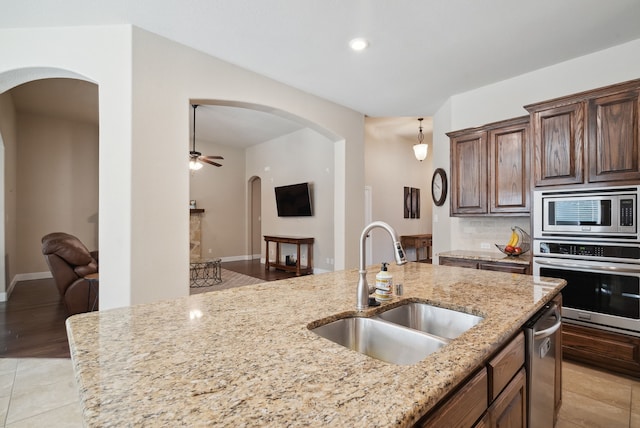 kitchen featuring light tile patterned floors, stainless steel appliances, light stone countertops, decorative backsplash, and sink