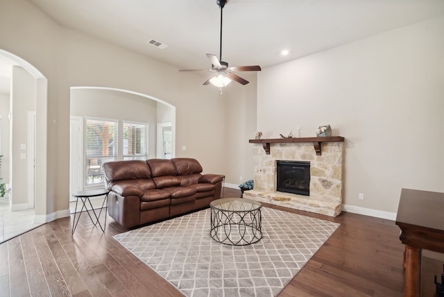 living room with lofted ceiling, a stone fireplace, ceiling fan, and wood-type flooring